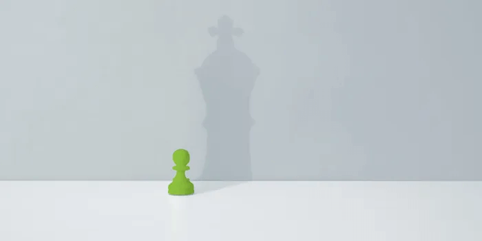 Graphics of a green pawn chess piece casting a shadow that looks like a king chess piece.