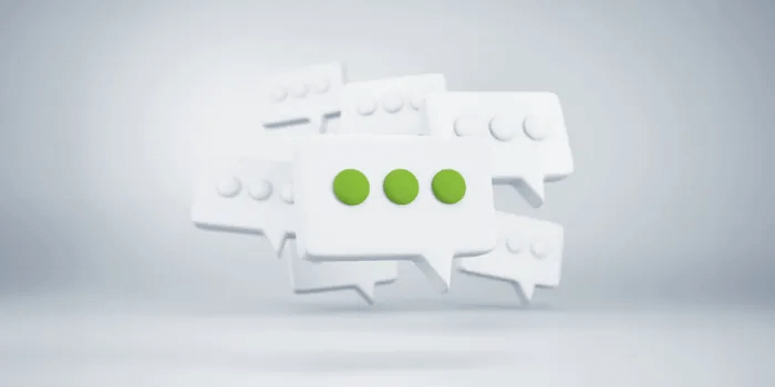 Graphics of white speech bubbles with one in the middle having a green ellipsis surrounded by other white bubbles with white ellipses.